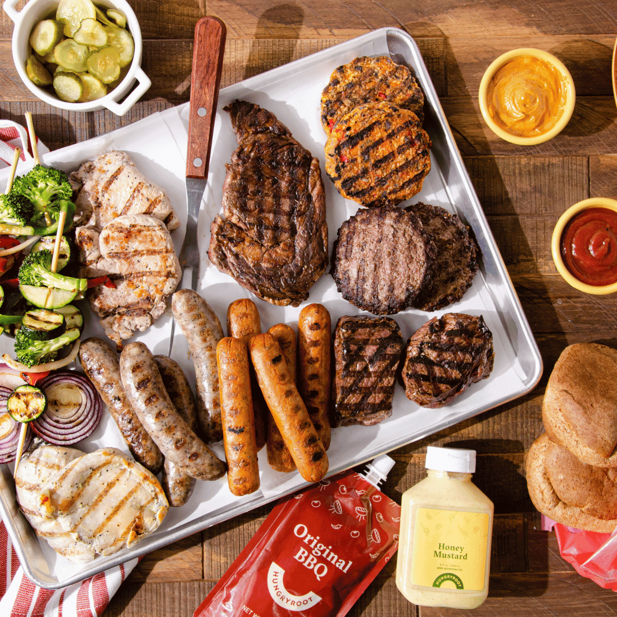A tablescape of mixed meats and sauces for a barbecue.