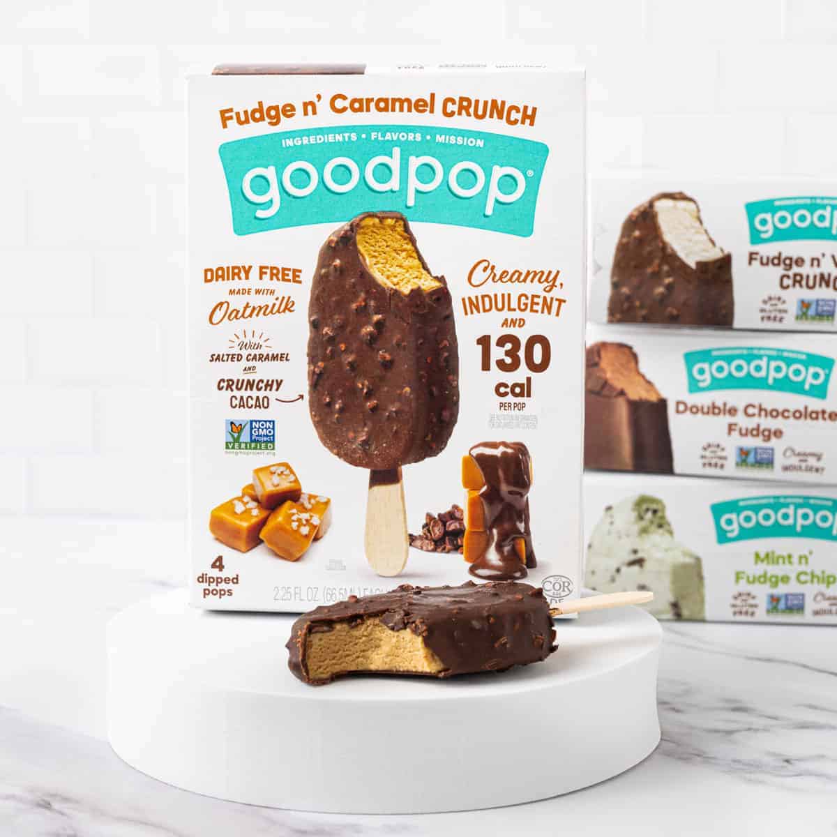 A box of GoodPop's Fudge n' Caramel Crunch dipped bars with a popsicle in front of it with a bite taken out.