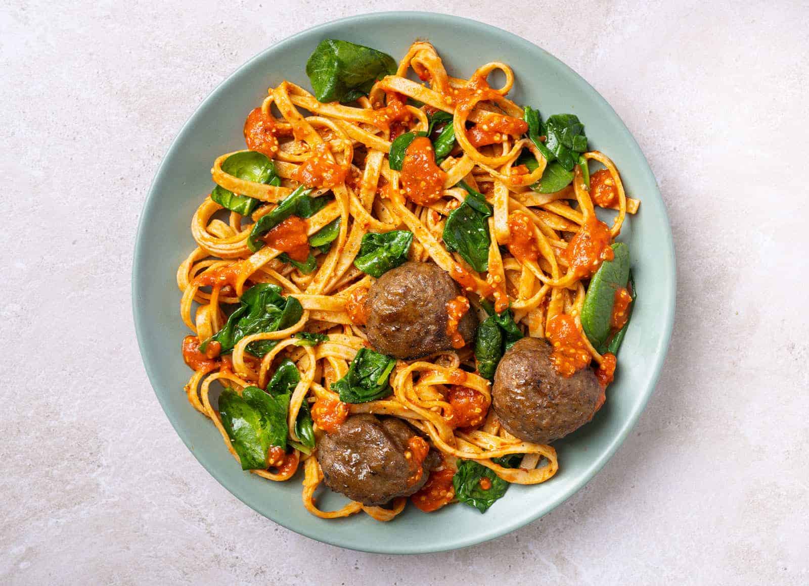 A Hungryroot dish of beef meatballs on a tomatoey linguine with spinach mixed in.